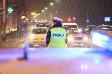 Policjanci ruchu drogowego kierują ruchem w czasie opadów śniegu. 