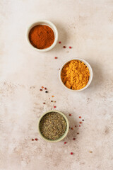 Various spices and seasonings: turmeric, paprika and provencal herbs on light brown stone background. Cooking background and copy space for text, top view.