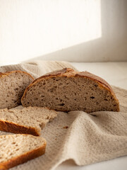 Homemade fresh wheat-rye bread on sourdough on a natural color linen napkin on a white background in the morning light