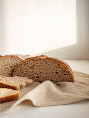 Homemade fresh wheat-rye bread on sourdough on a natural color linen napkin on a white background in the morning light