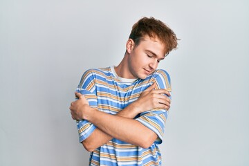 Young caucasian man wearing casual striped t shirt hugging oneself happy and positive, smiling confident. self love and self care