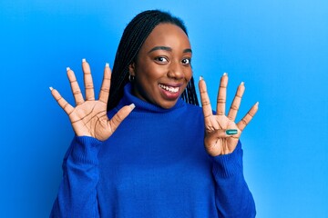 Young african american woman wearing casual winter sweater showing and pointing up with fingers...