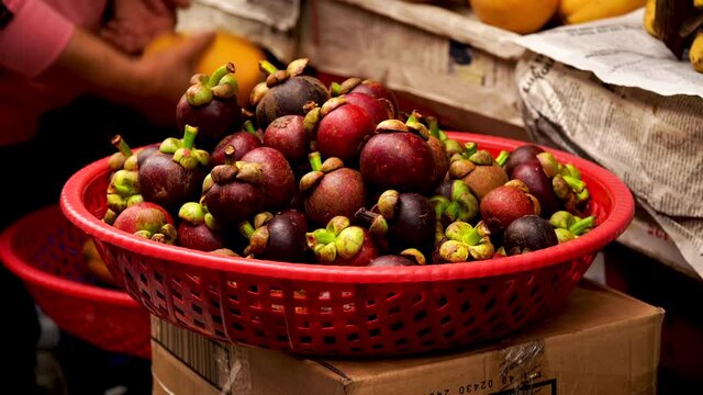 Basket of Mangosteen fruit in an open air market in Hoi An, Vietnam. Mangosteen is a fruit endemic to Southeast Asia 