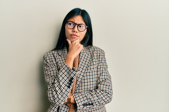 Young chinese woman wearing business style and glasses thinking worried about a question, concerned and nervous with hand on chin