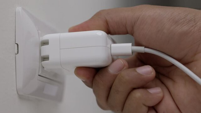 Close up male hand put on the Electric adapter smartphone or laptop plug. Electrical wires and power strips in the house