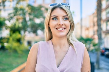 Young blonde woman smiling happy walking at the city.