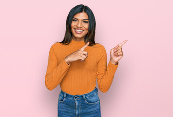 Young latin transsexual transgender woman wearing casual clothes smiling and looking at the camera pointing with two hands and fingers to the side.