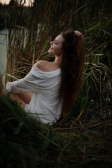 Sexy girl in a white shirt on nature in the evening in the sunset rays of the sun