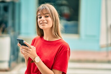Caucasian teenager girl smiling happy using smartphone at the city.