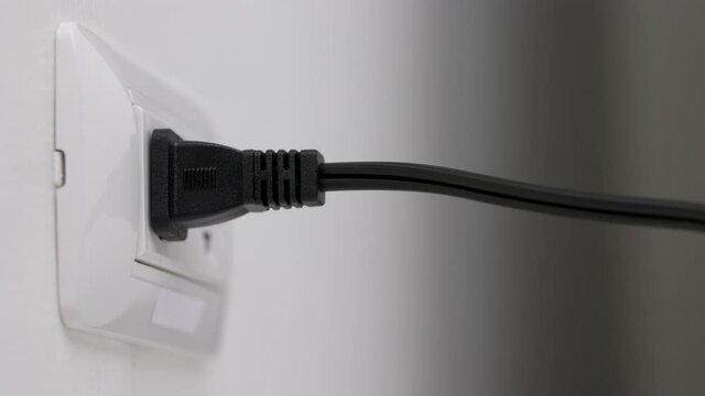 Hand holding Electric plug put on multiple socket. Electrical equipment, electrical wires and power strips in the house. Earth Hour saving electrical energy.