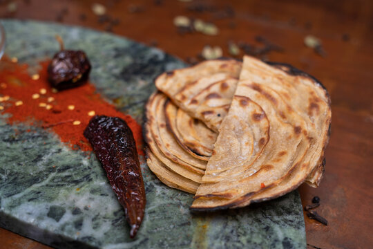 Aloo Paratha / Indian Potato stuffed Flat bread in white plate. on wooden table.