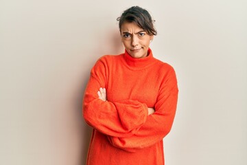 Young hispanic woman wearing casual winter sweater skeptic and nervous, disapproving expression on...
