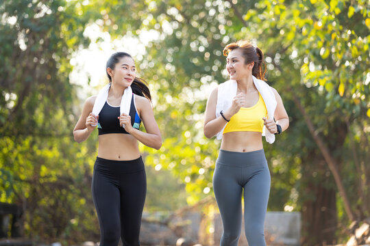 asian athletics couple woman jogging and exercising together in public park in the evening