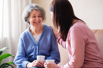 Daughter visits an elderly mother and have fun together - An elderly woman and a young woman are...