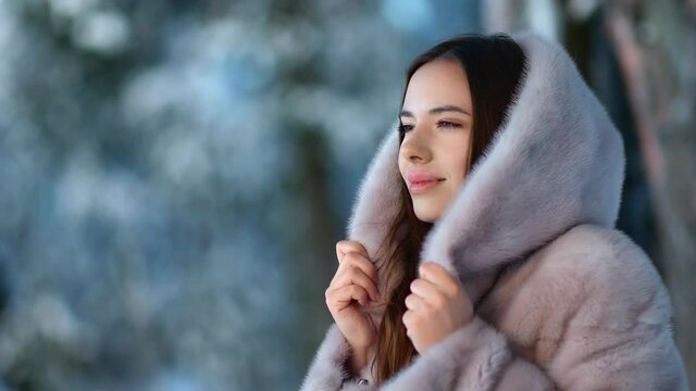 Pretty lady in gray hood fur coat at winter forest park. Medium close up shot on 4k RED camera
