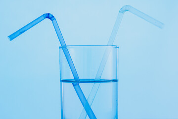 A glass of clear blue water with two drinking straws. The concept of World Water Day.