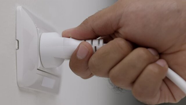 Hand remove Electric plug on socket. Electrical equipment, electrical wires and power strips in the house. Earth Hour saving electrical energy.