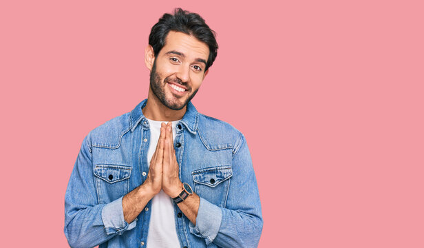 Young hispanic man wearing casual clothes praying with hands together asking for forgiveness smiling confident.