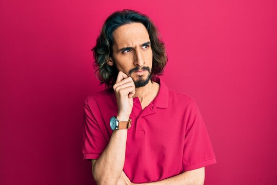 Young hispanic man wearing casual clothes thinking concentrated about doubt with finger on chin and looking up wondering