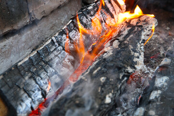 Glowing embers in hot red color, abstract background. The hot embers of burning wood log fire. Firewood burning on grill. Texture fire bonfire embers.