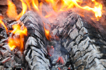 Glowing embers in hot red color, abstract background. The hot embers of burning wood log fire. Firewood burning on grill. Texture fire bonfire embers.