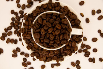 A mug with coffee surrounded by coffee beans on a white background. Coffee beans in a coffee mug