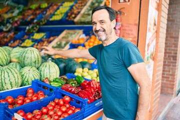 Middle age man with beard smiling happy shopping vegetables at the grocery supermarket