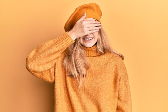 Beautiful young caucasian girl wearing french look with beret smiling and laughing with hand on face covering eyes for surprise. blind concept.