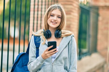 Beautiful caucasian student teenager smiling happy using smartphone at the city.