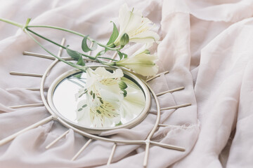 Beautiful alstroemeria flowers on boho mirror on soft fabric. Spring aesthetics. Womens day