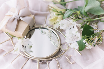 Happy Womens and Mothers day. Stylish gift, jewelry, spring flowers on boho mirror on soft fabric