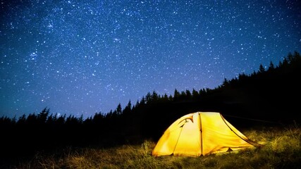 Glowing camping tent in the night mountain forest under the twinkling starry sky