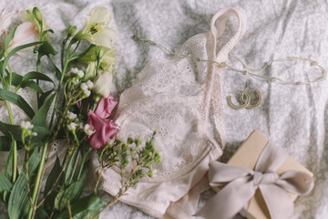 Obraz na płótnie Canvas Stylish lingerie, gift, modern jewelry and spring bouquet on bed. Soft image. Happy Women's day