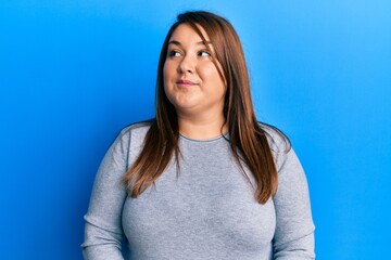 Fototapeta premium Beautiful brunette plus size woman wearing casual clothes smiling looking to the side and staring away thinking.