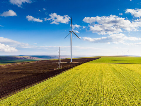 Beautiful bright Landscape with a Windfarm on a sunny day with a sky full of clouds and colorful foreground with green-yellowish grass