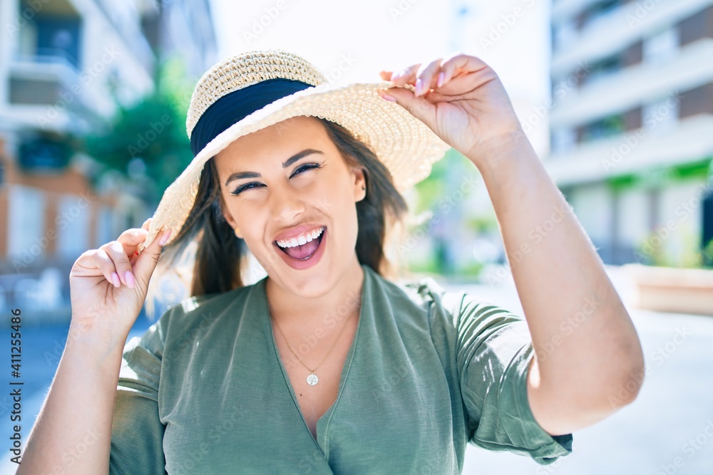 Wall mural Young hispanic woman on vacation smiling happy walking at street of city