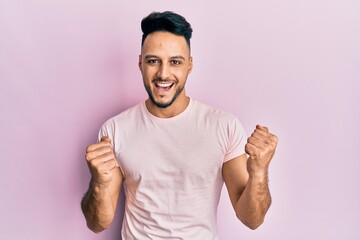 Young arab man wearing casual clothes celebrating surprised and amazed for success with arms raised...