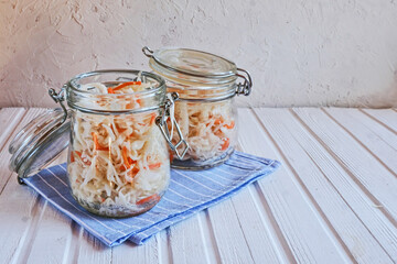 Homemade sauerkraut with carrots in a glass jar on wooden table. Fermented vegetables. Vegetarian vegan food. Sauercraut- cut, fermented cabbage, german and russian style cuisine.