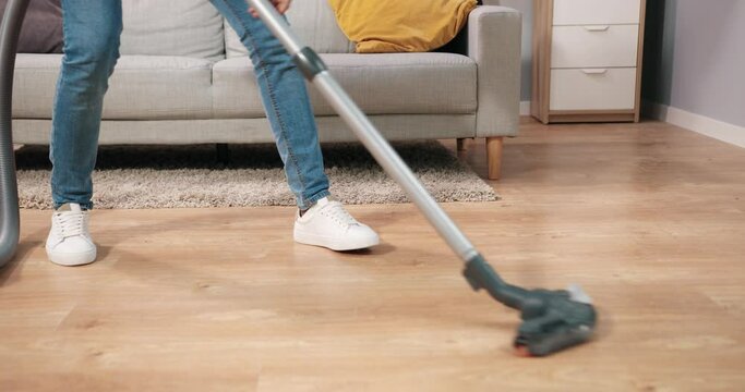 Close up of African American happy positive young man vacuuming home cleaning cozy room dancing making funny moves pretending to play on guitar, guy using vacuum in apartment, housework concept