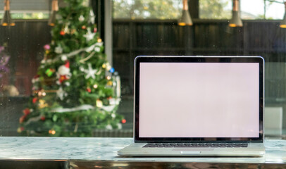 A laptop computer with a blank white screen and a blurred Christmas tree background.