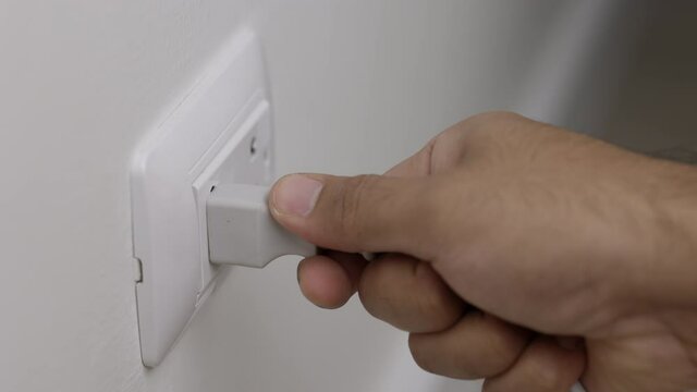 Hand holding Electric plug put on multiple socket. Electrical equipment, electrical wires and power strips in the house. Earth Hour saving electrical energy.