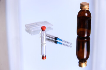 a bottle of vaccine, a syringe and a medical mask on a glass surface