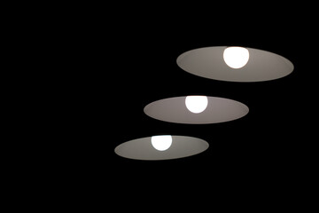 Three minimalistic lamps on black ceiling background