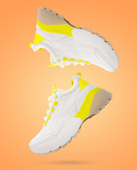 Fototapeta premium Modern sport sneakers of light color flying on a orange gradient background.