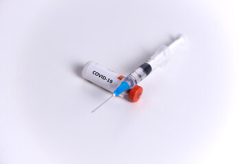 a bottle of vaccine, a syringe and a medical mask on a glass surface