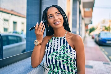 Young african american woman smiling happy listening audio message using smartphone at the city.