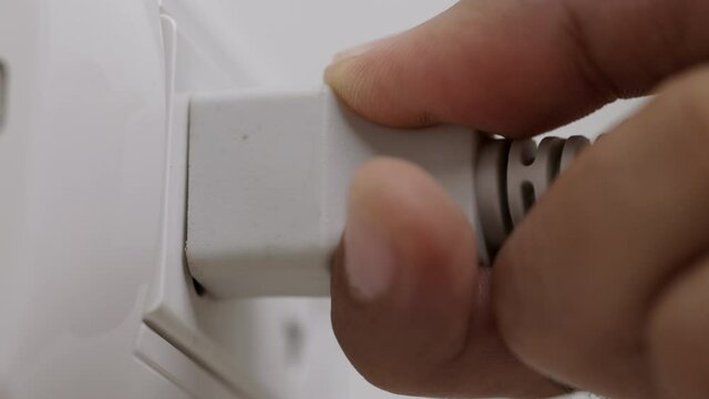 Hand holding Electric plug put on multiple socket. Electrical equipment, electrical wires and power strips in the house. Earth Hour saving electrical energy.