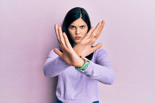 Young hispanic woman wearing casual clothes rejection expression crossing arms and palms doing negative sign, angry face