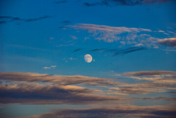 
Moon in the afternoon among colorful clouds