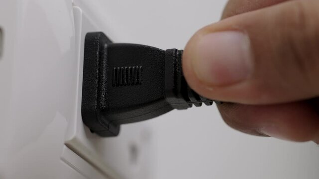 Hand remove Electric plug on socket. Electrical equipment, electrical wires and power strips in the house. Earth Hour saving electrical energy.